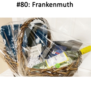 This basket includes a blue throw, tote bag, wine, gift card, and wine glass.