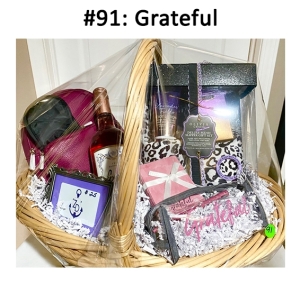 This basket includes a bag, pad & pen, slipper gift set, gift card, eye mask, wine, and a purse.